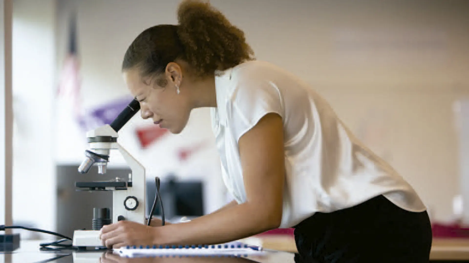 alumna con microscopio en clase de ciencias en el curso escolar en estados unidos en Cotter Schools
