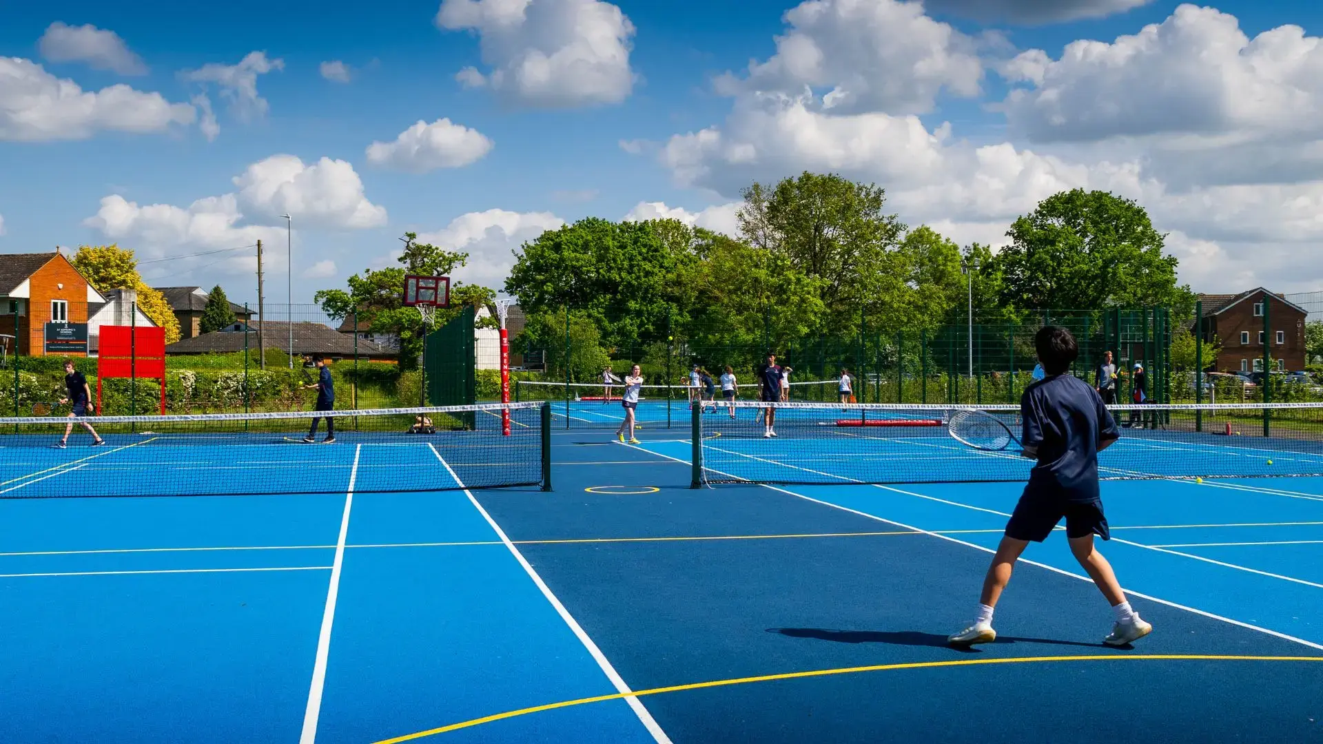 alumnos practicando tenis en las pistas outdoor del campus en el curso escolar en inglaterra en Kent College