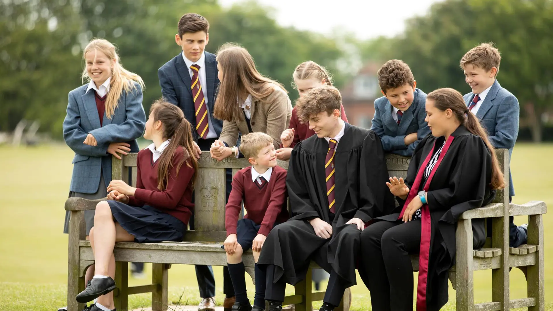 alumnos uniformados en un banco del cesped del campus del colegio en el curso escolar en inglaterra en Scarborough College
