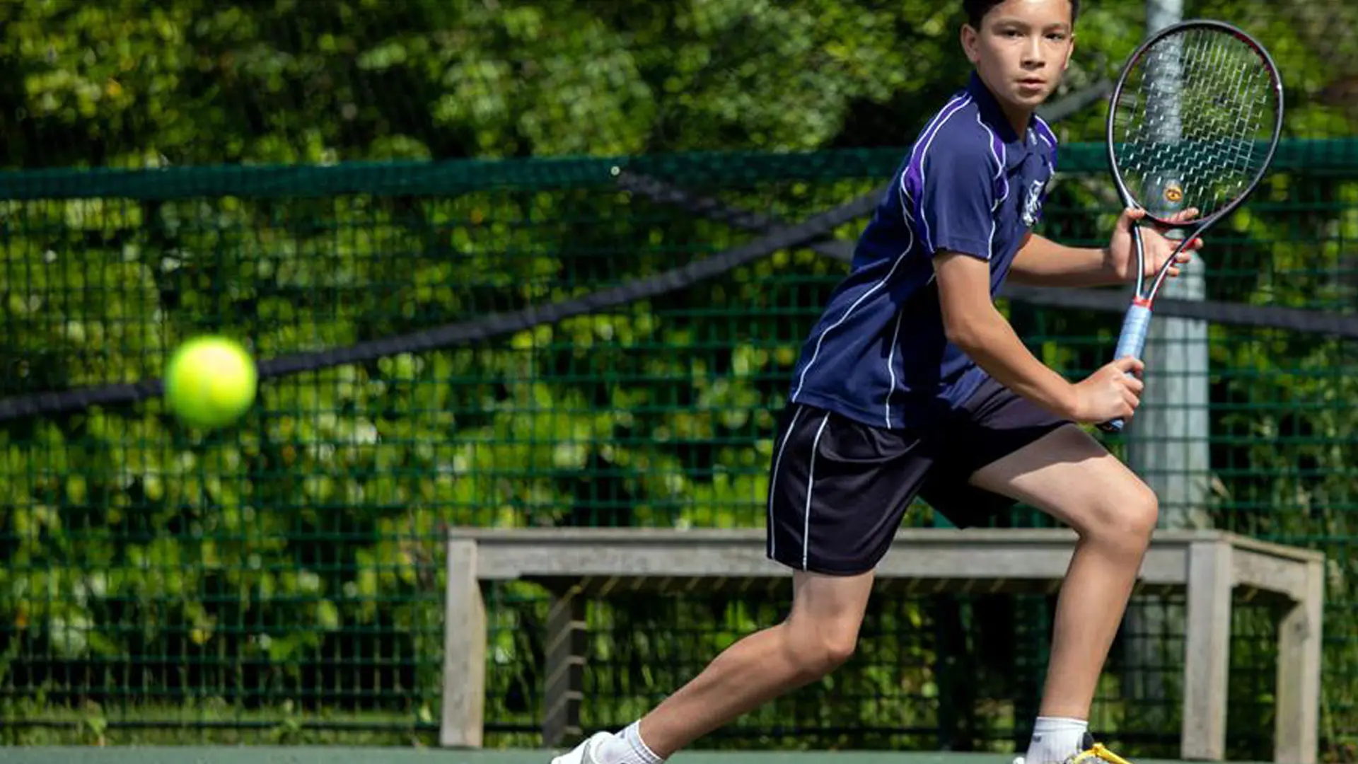 alumno jugando a tenis en la pista de tenis del colegio en el curso escolar en inglaterra en Sherfield School