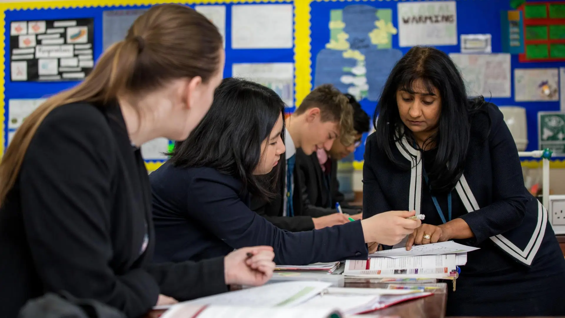 alumnos recibiendo ayuda de su profesora en el aula en el curso escolar en inglaterra en Sherfield School