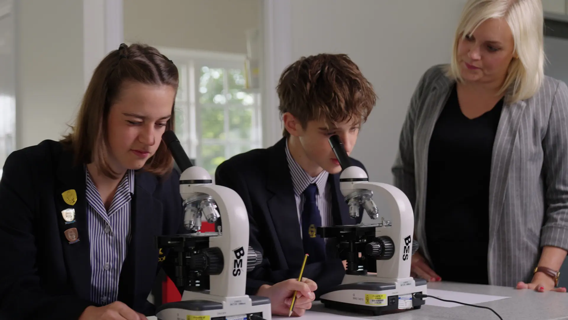 alumnos con microscopios en la clase de cienciasen el curso escolar en inglaterra en Sidcot School