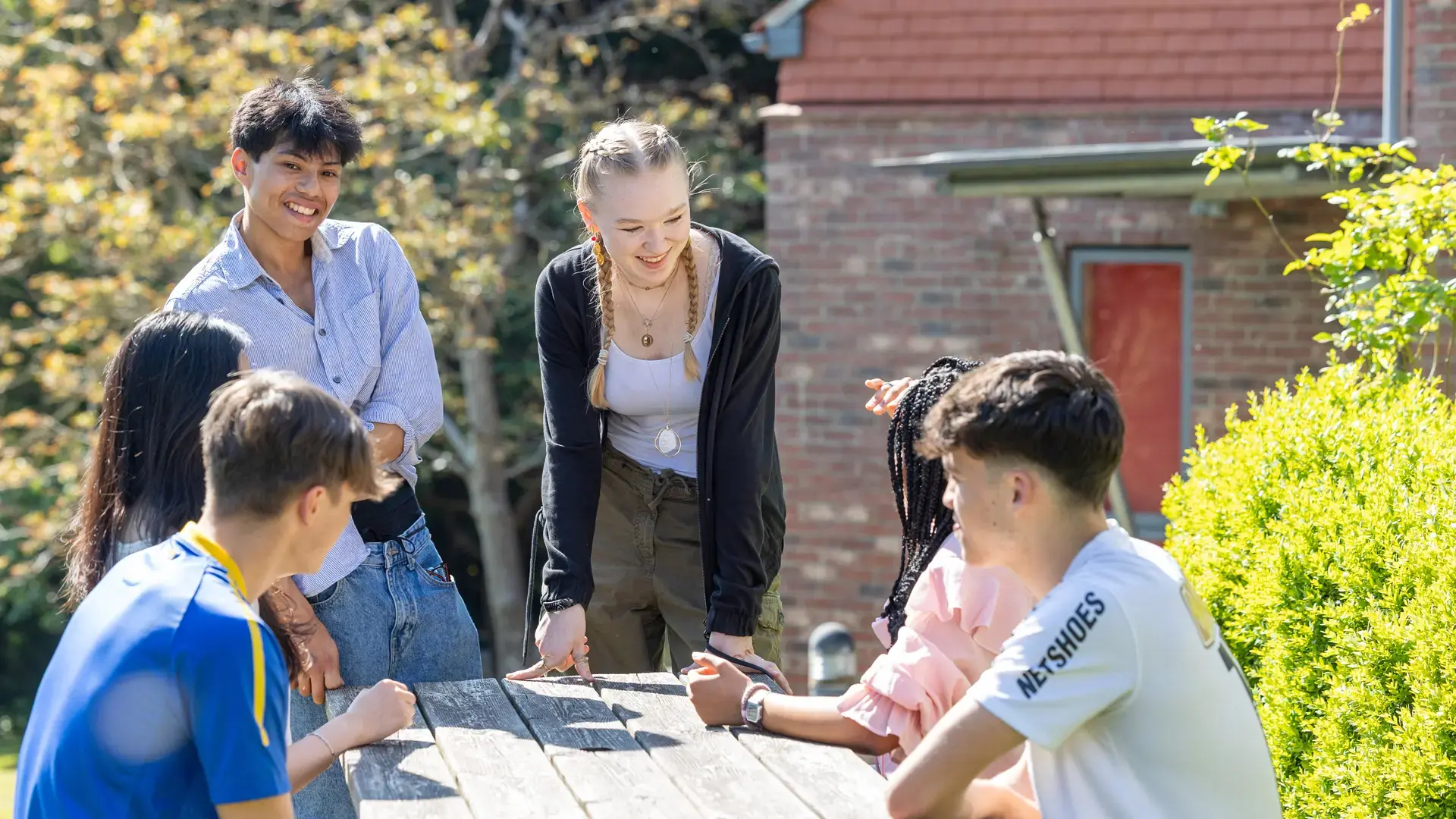 alumnos charlando en una mesa de picnic en las zonas exterior del campus en el curso escolar en inglaterra en Sidcot School