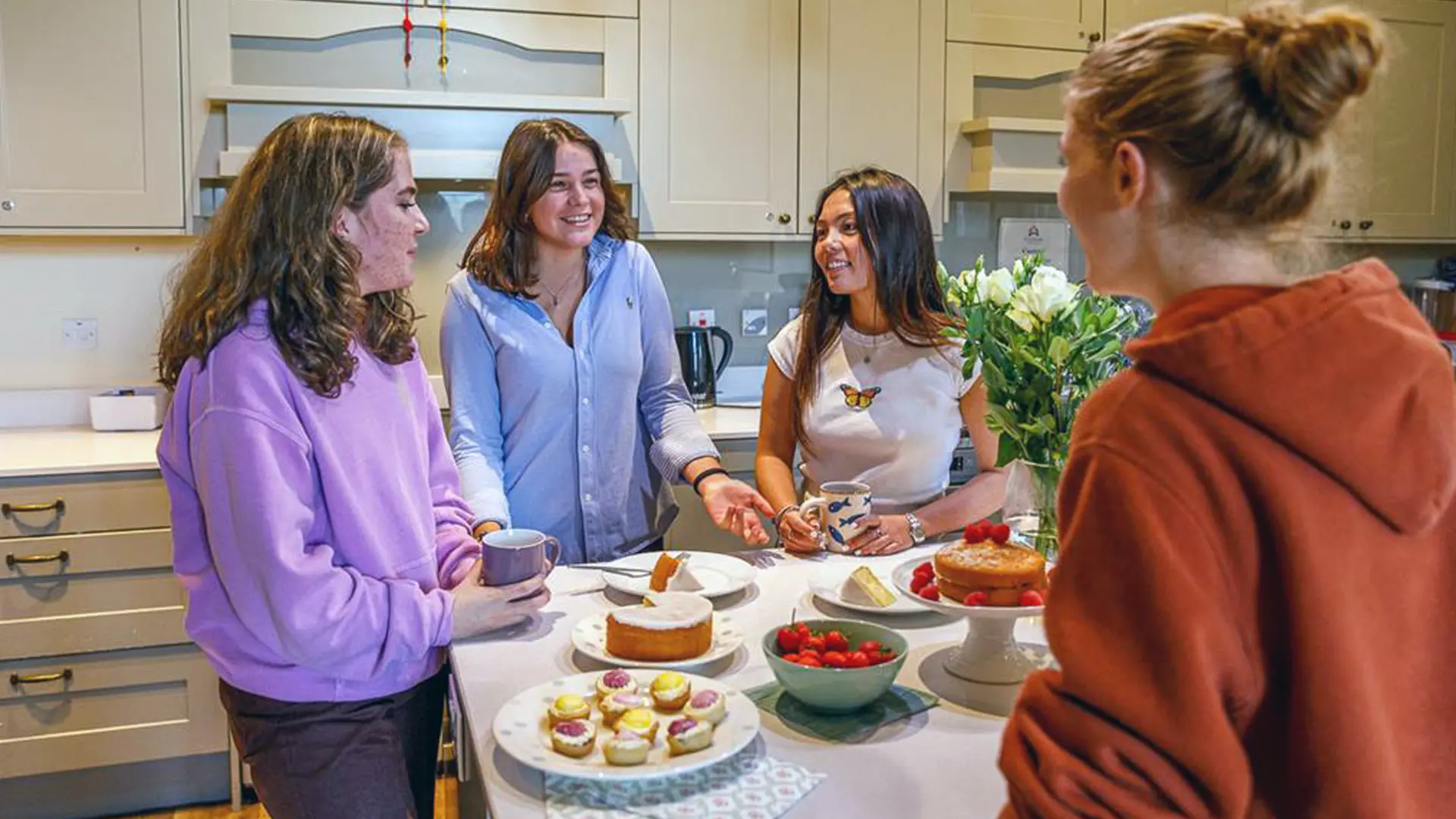 cuatro alumnas en la cocina de la residencia comiendo snacks en el curso escolar en inglaterra en St. Leonards School